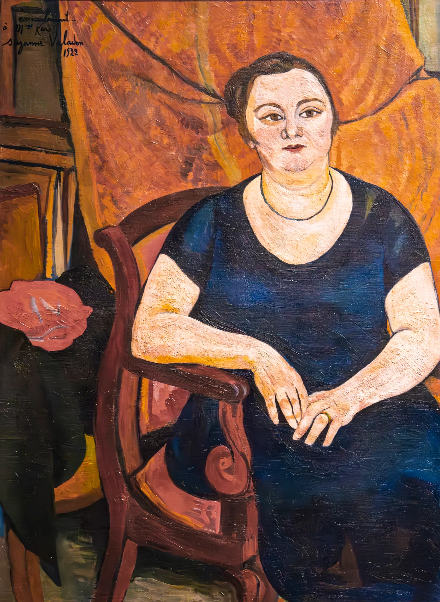 Portrait of Nora Kars Portrait of Nora Kars by Suzanne Valadon. An expressive oil portrait of a seated woman in a dark blue dress against a warm, draped background.