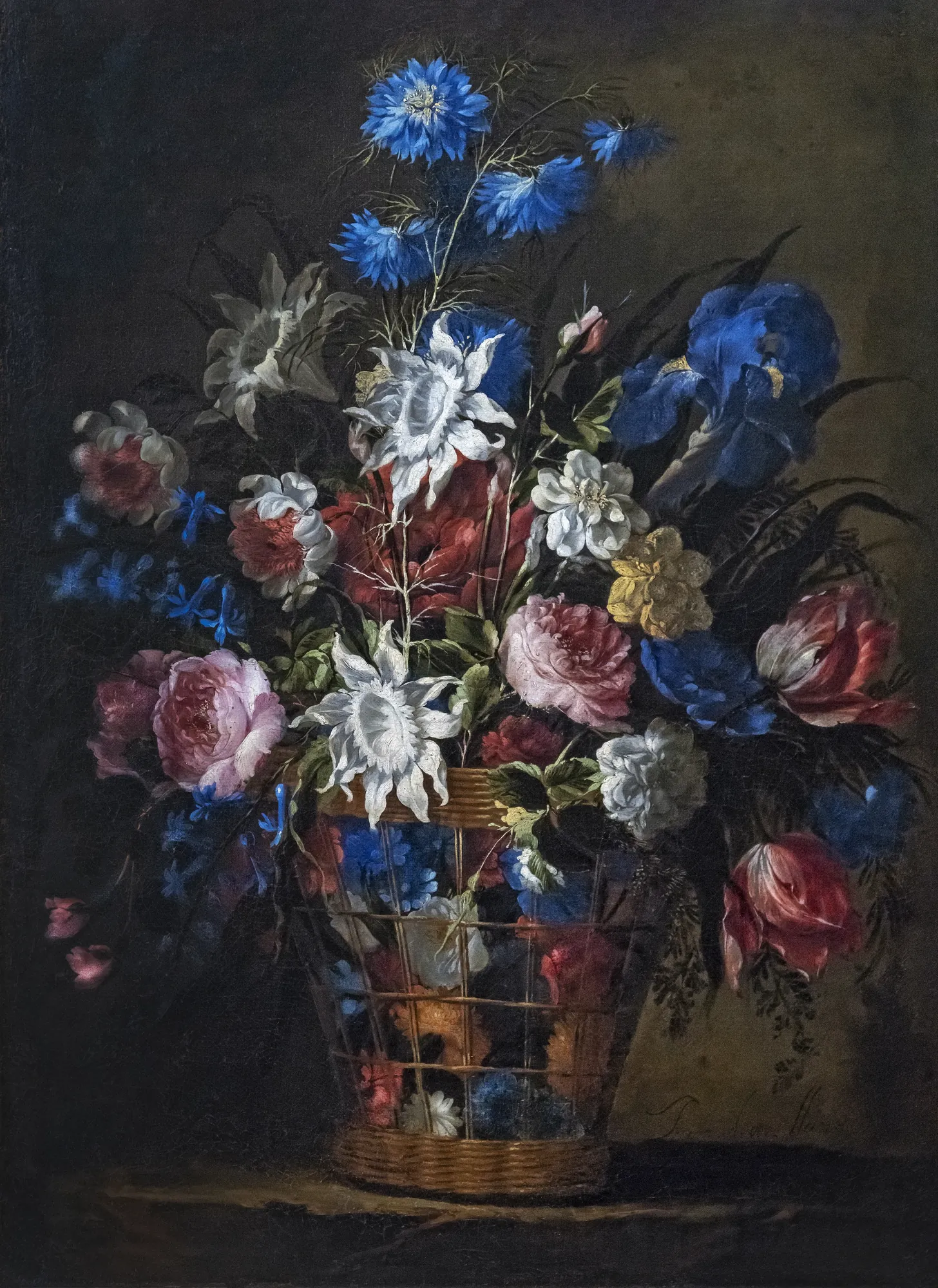 Basket with Flowers Basket with Flowers by Juan de Arellano. An ornate wicker basket filled with a dense, colorful arrangement of roses, irises, and lilies against a dark, atmospheric background.