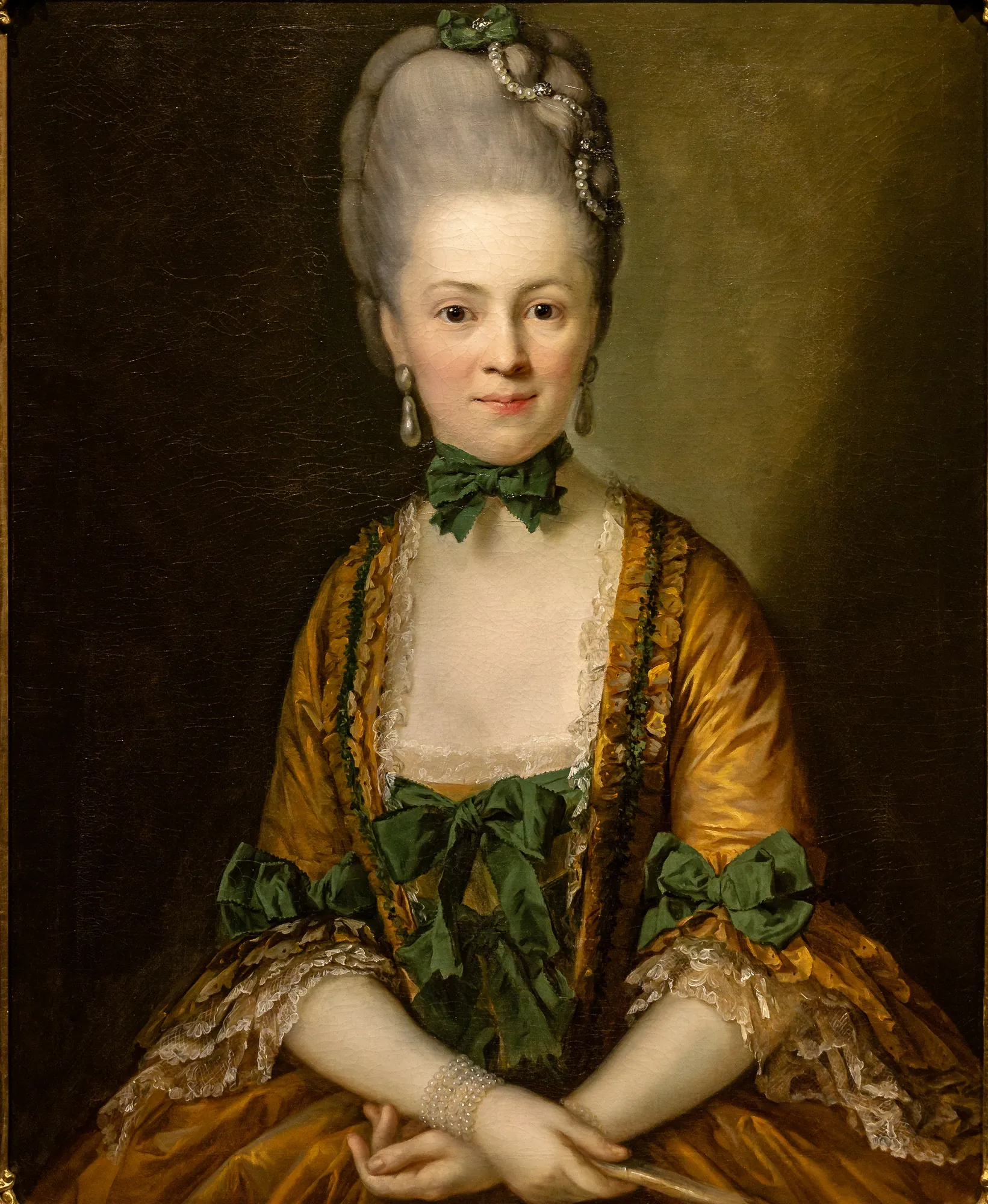 Henriette von Carlowitz Henriette von Carlowitz by Anton Graff. A half-length portrait of a woman with high powdered hair, wearing a shimmering gold silk gown decorated with green ribbons and pearls.