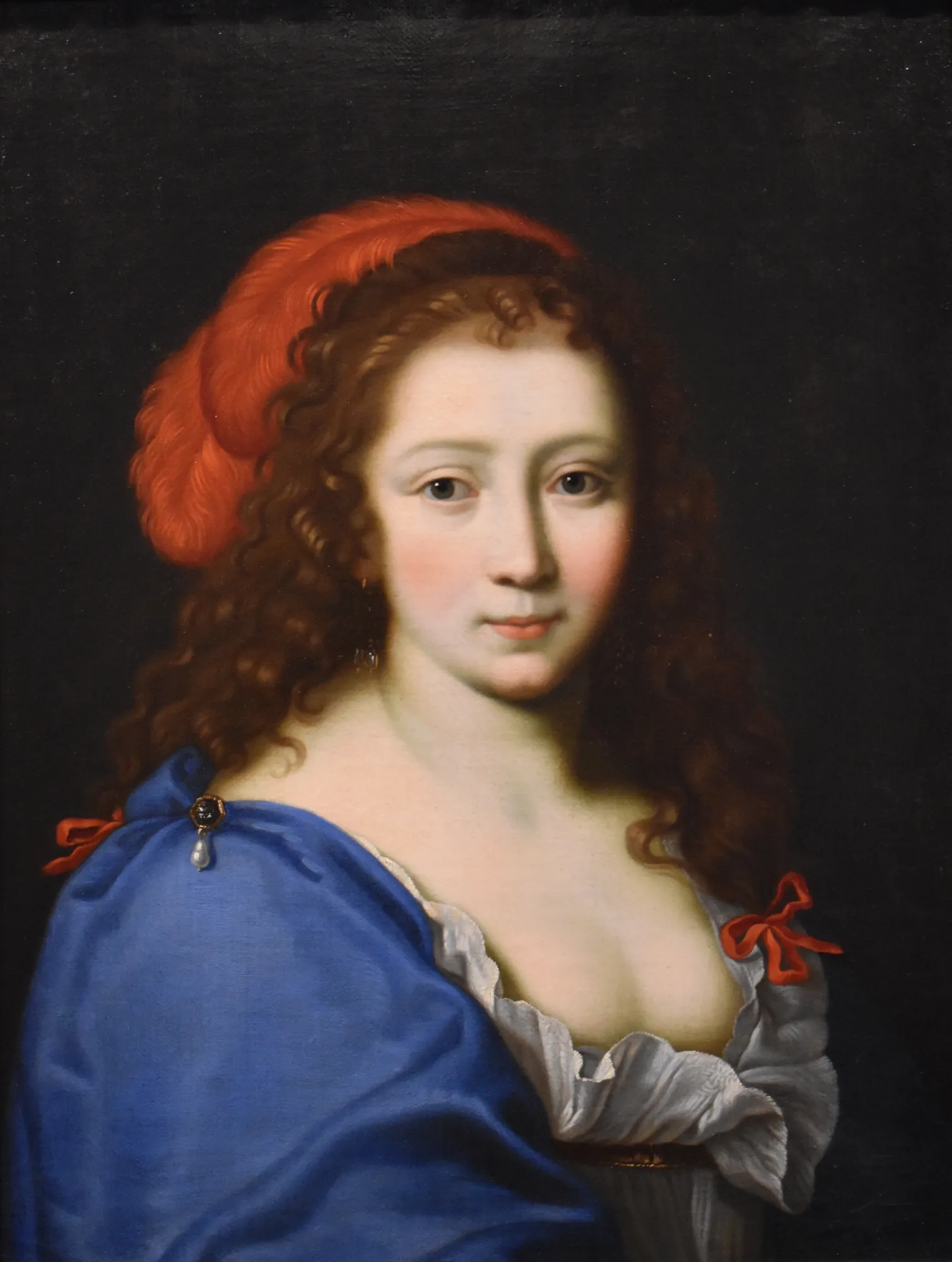 Portrait of Hortense Mancini Portrait of Hortense Mancini by Nicolas Mignard. A half-length portrait of a young woman with curly brown hair wearing a red feathered cap, a blue cloak, and a white chemise.