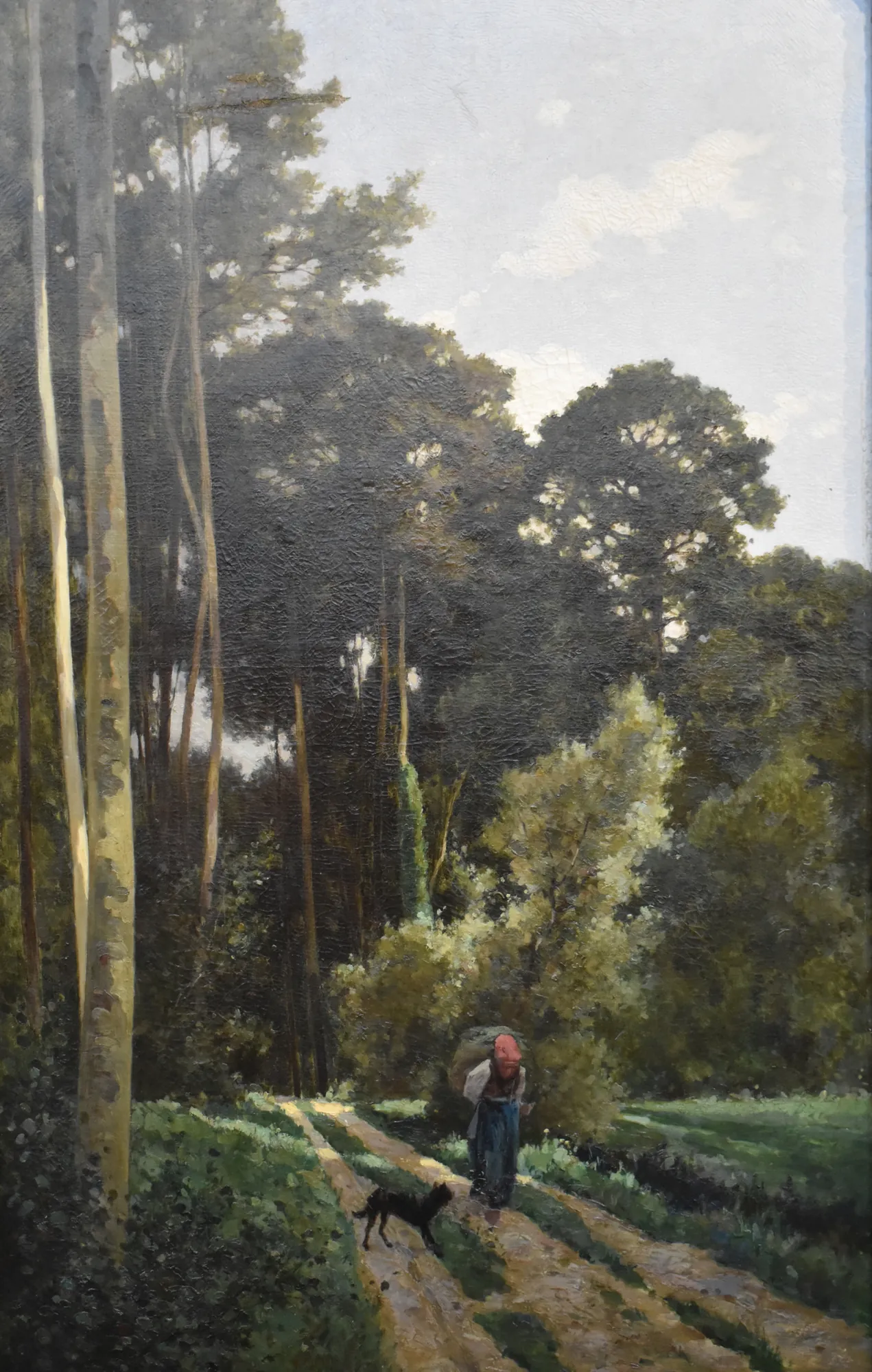 Lisière d'un bois Lisière d'un bois by Louis-Félix-Achille Dien. A figure in a red cap walks a black dog along a sun-dappled dirt path at the edge of a dense forest.