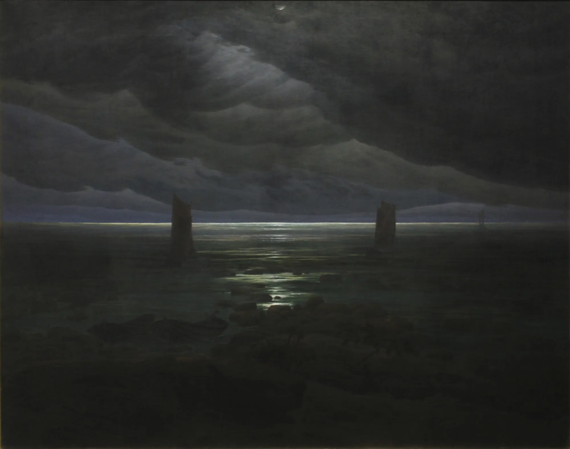 Sea Shore in Moonlight Sea Shore in Moonlight by Caspar David Friedrich. A dark nocturnal seascape featuring the moon reflecting on a rocky shore and calm water beneath heavy clouds.