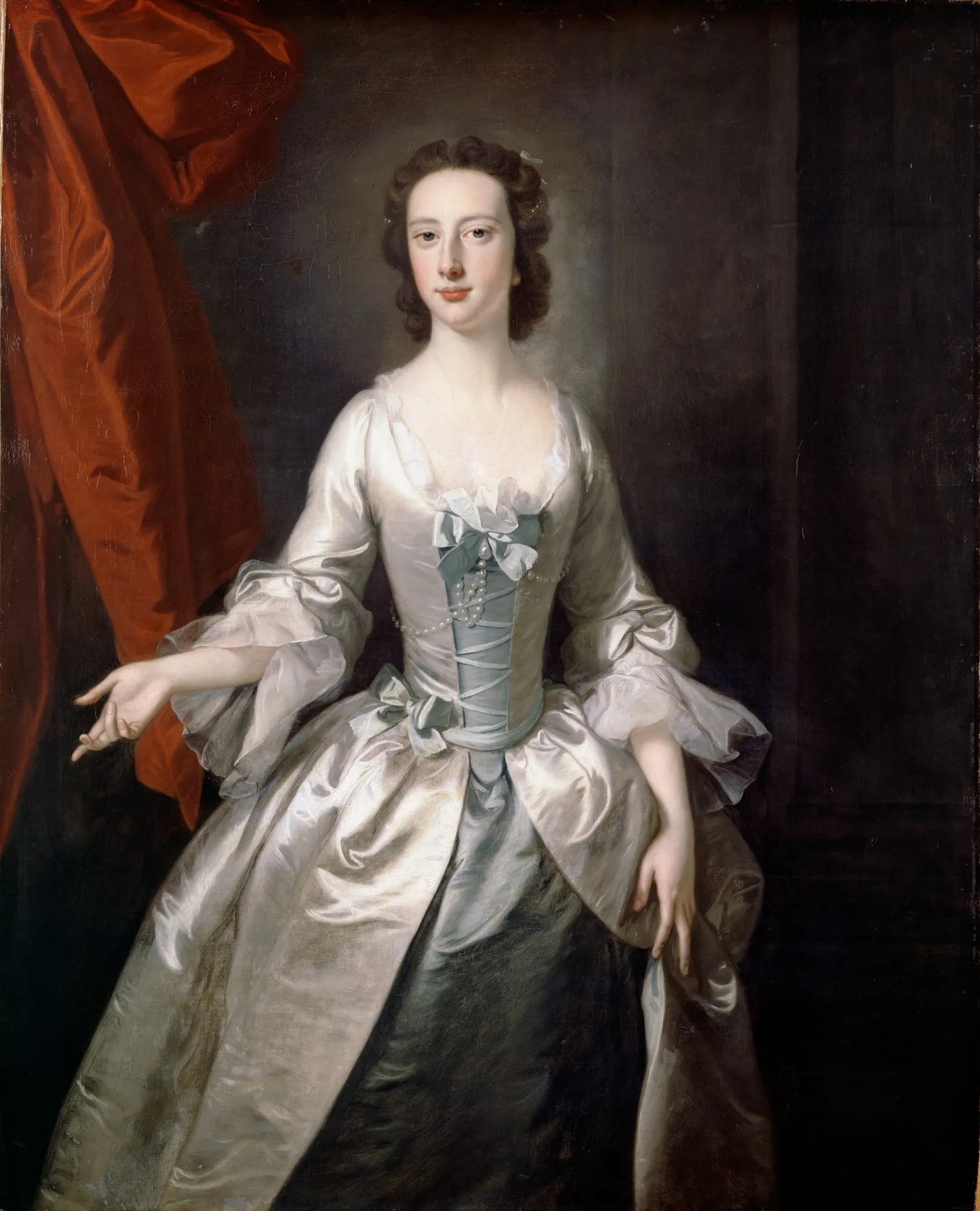 Portrait of a Lady Portrait of a Lady by Thomas Hudson. A three-quarter length portrait of a woman in an elegant silver-white silk gown with blue ribbons and a red curtain in the background.