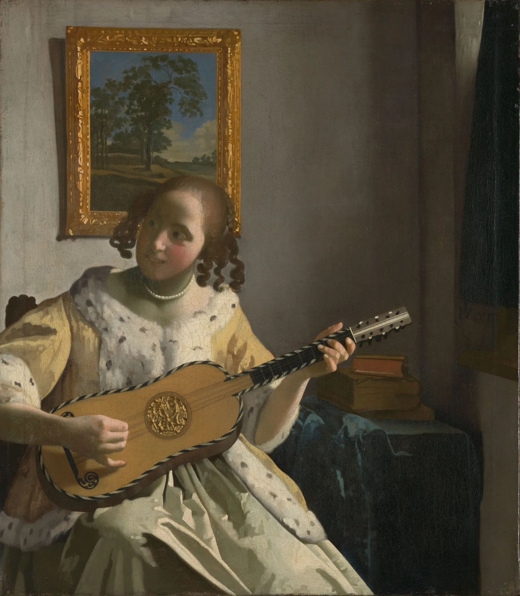 The Guitar Player The Guitar Player by Johannes Vermeer. A young woman in a fur-trimmed yellow jacket sits playing a guitar in an interior, with a framed landscape visible behind her.