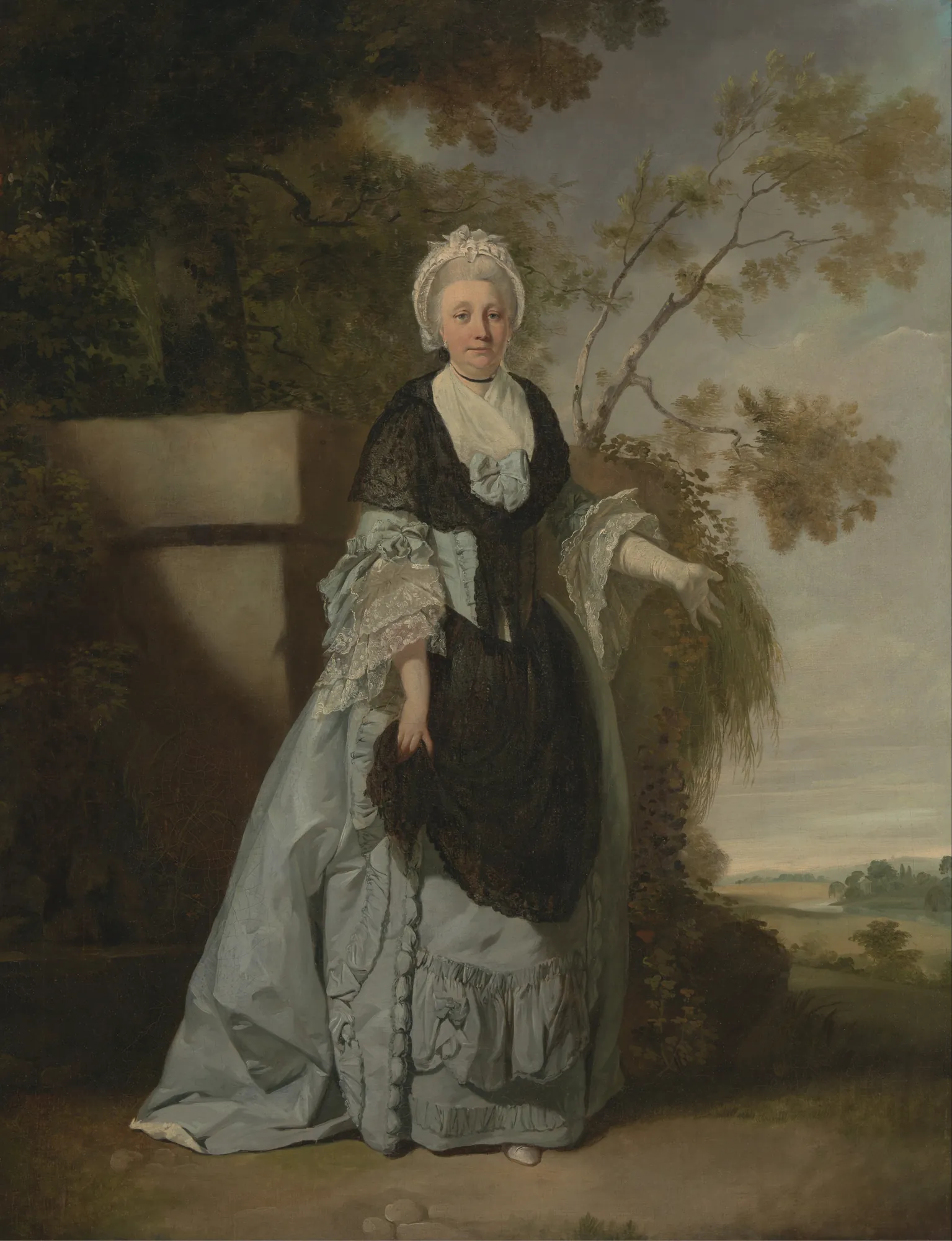 Mrs. Bentley Mrs. Bentley by Francis Wheatley. A full-length portrait of a woman in an elegant blue gown and black lace shawl, standing before a stone plinth in a wooded landscape.