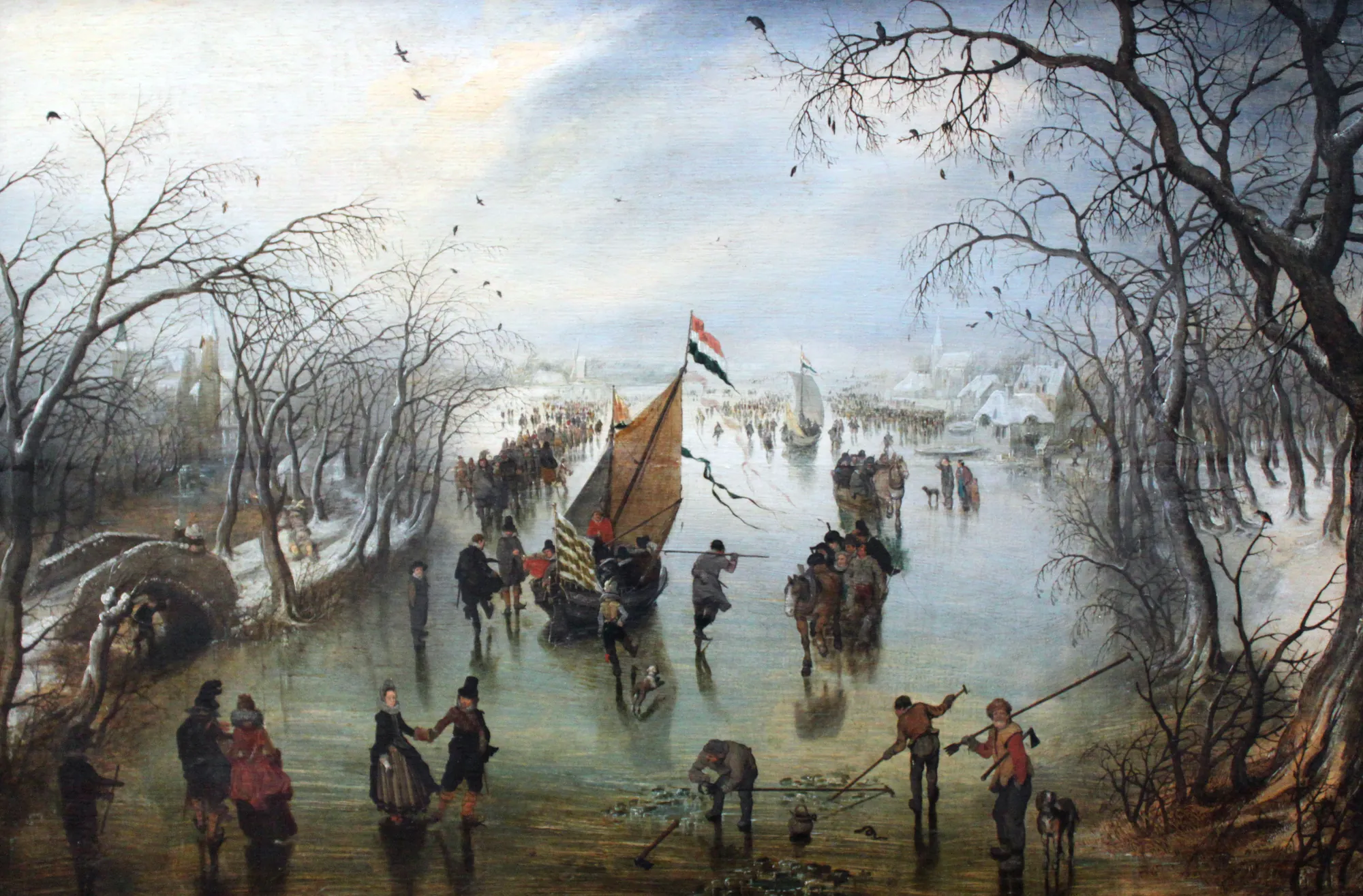 Winter Winter by Adriaen van de Venne. A bustling 17th-century Dutch winter scene featuring numerous figures skating and working on a frozen river framed by bare trees.