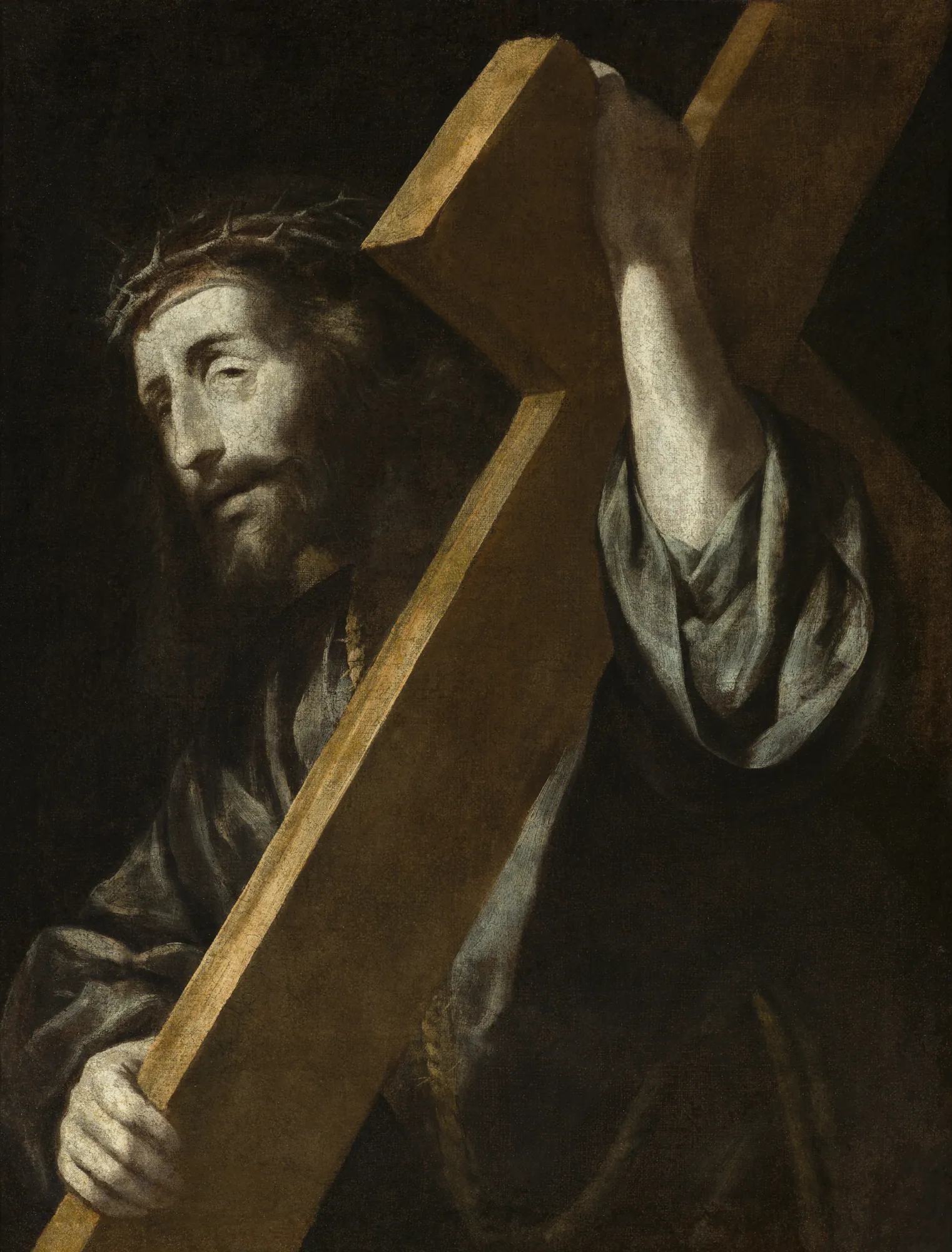 Jesús Nazareno Jesús Nazareno by Unknown Artist. A high-contrast Baroque painting of Jesus with a crown of thorns carrying a heavy wooden cross against a deep black background.